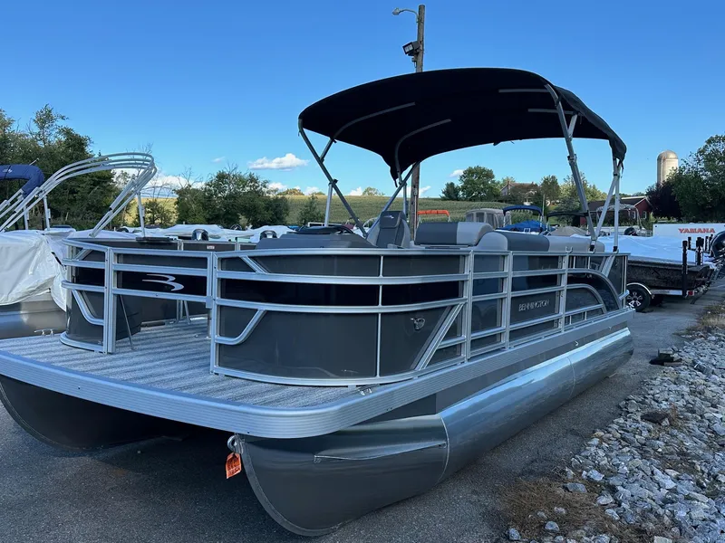 Slide: The Image of 2025 Bennington 21 SF Family pontoon boat with four fishing seats, parked outdoors. - 13