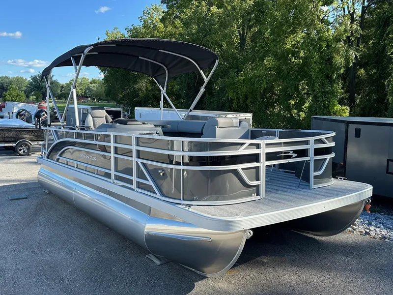 Slide: The Image of 2025 Bennington 21 SF pontoon boat with canopy and fishing seats, parked outdoors. - 14