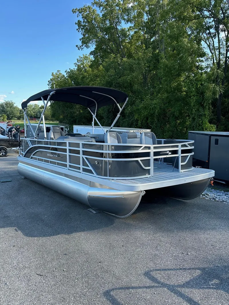 Slide: The Image of 2025 Bennington 21 SF pontoon boat with canopy and four fishing seats, parked outdoors. - 29