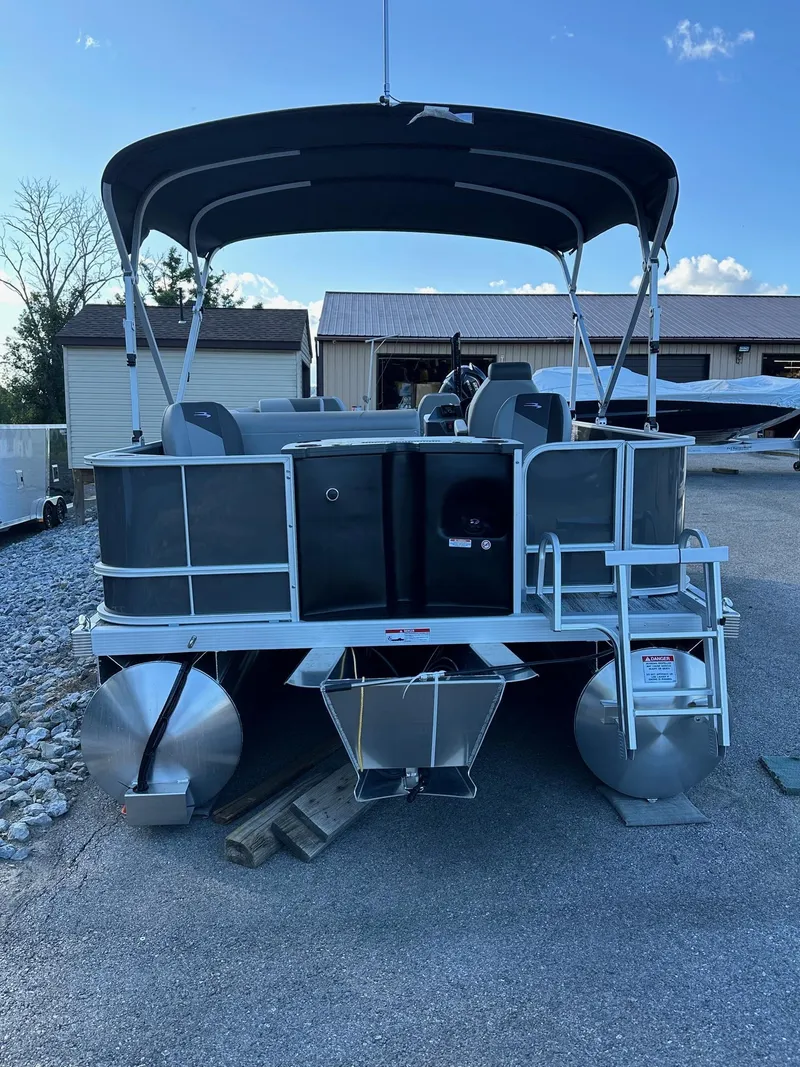 Slide: The Image of 2025 Bennington 21 SF pontoon boat with canopy and fishing seats, parked outdoors. - 30