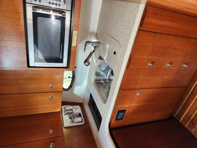 Slide: The Image of 2004 Tiara Yachts 38 Open kitchen with microwave, sink, and wooden cabinetry. - 19