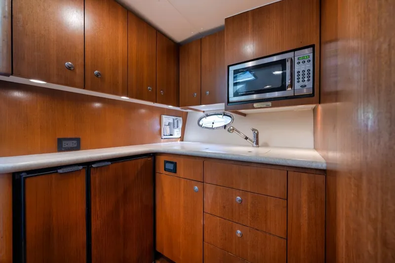 Slide: The Image of 2004 Tiara Yachts 38 Open galley with wood cabinets, microwave, and compact fridge. - 47