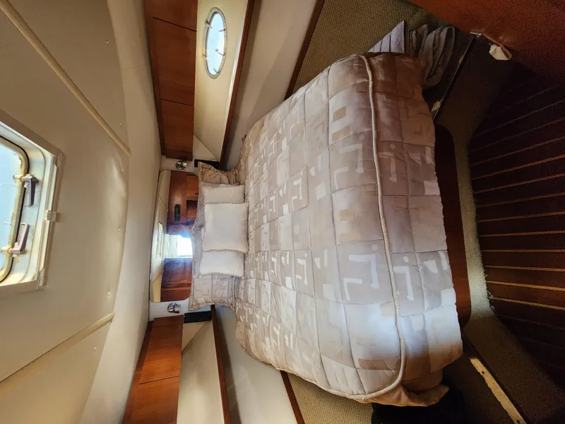 Slide: The Image of Interior cabin of 2004 Tiara Yachts 38 Open, featuring a cozy bed and porthole window. - 6