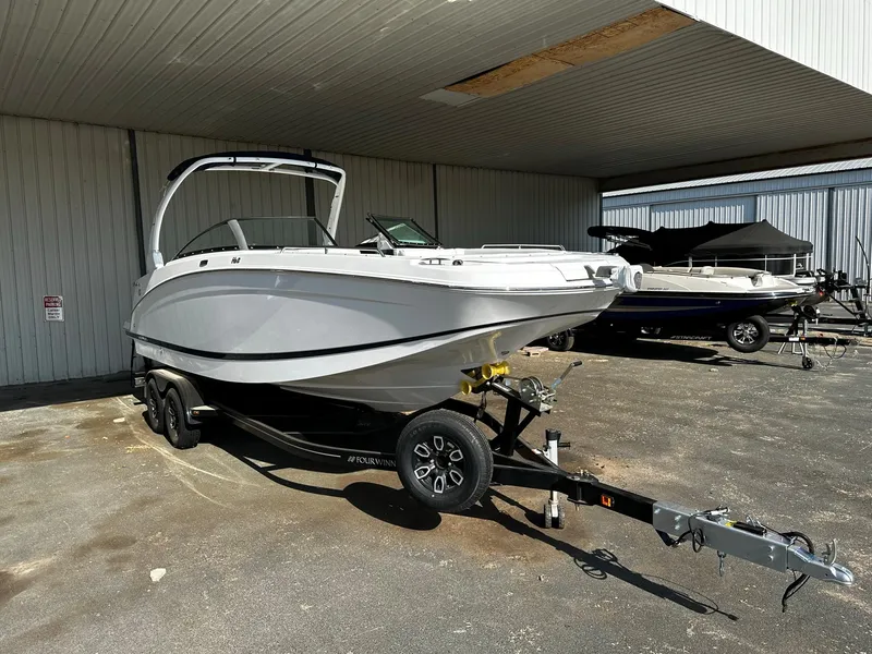 Slide: The Image of 2023 Four Winns HD8 OB boat on a trailer under a metal canopy. - 11