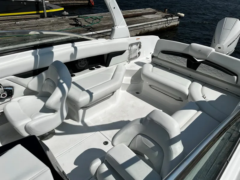 Slide: The Image of 2023 Four Winns HD8 OB boat interior with white seating and dock in background. - 27