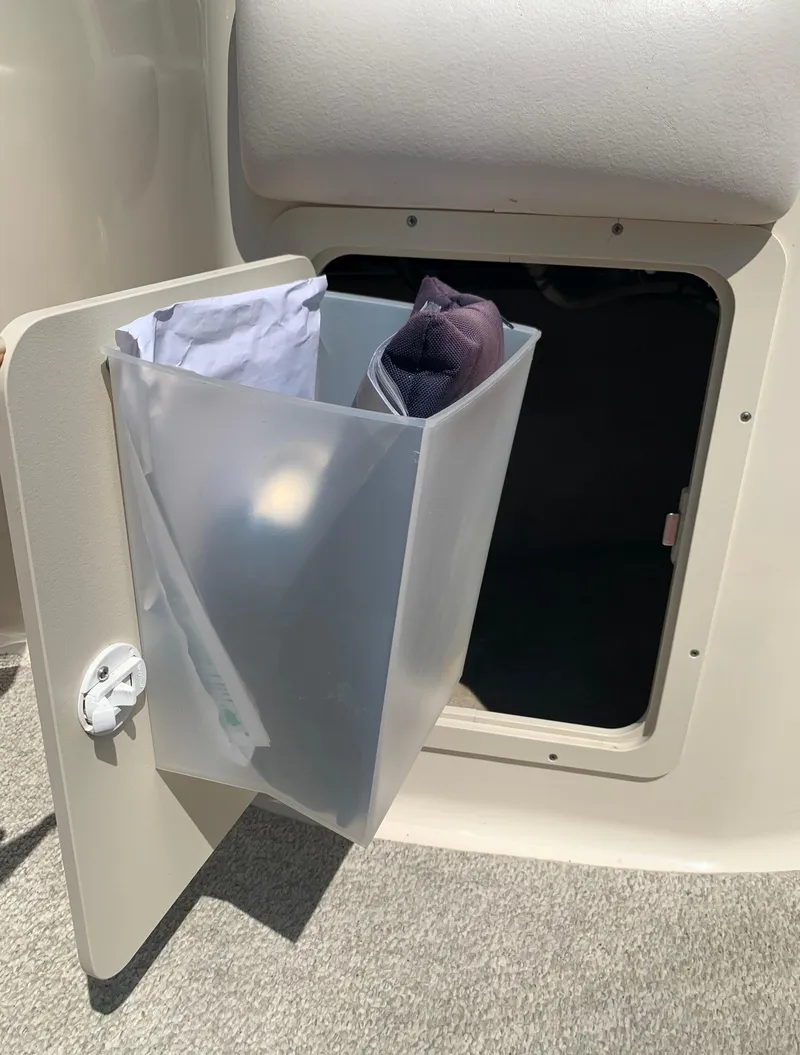 Slide: The Image of Storage compartment on a 2004 Crownline 270 BR boat with an open door and trash bin. - 33