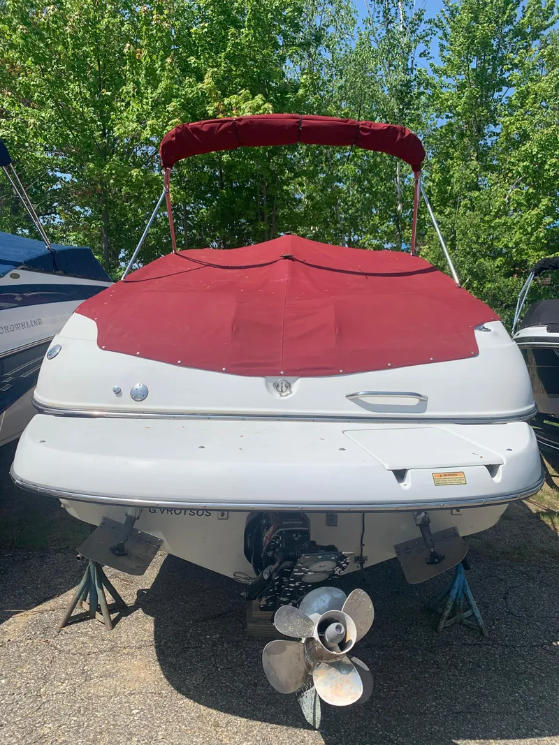 Slide: The Image of 2004 Crownline 270 BR boat with red cover and propeller, parked on stands. - 4