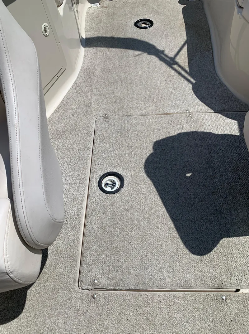 Slide: The Image of 2004 Crownline 270 BR boat interior with carpeted floor and storage hatch. - 42