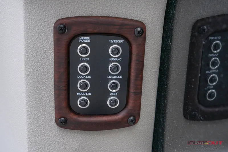 Slide: The Image of Control panel of 2023 South Bay L-Lounge Tri-Toon 150HP boat with various switches. - 22