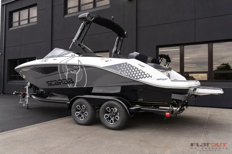 Slide: The Image of 2023 Scarab 215 ID boat on a trailer, parked outside a building. - 2