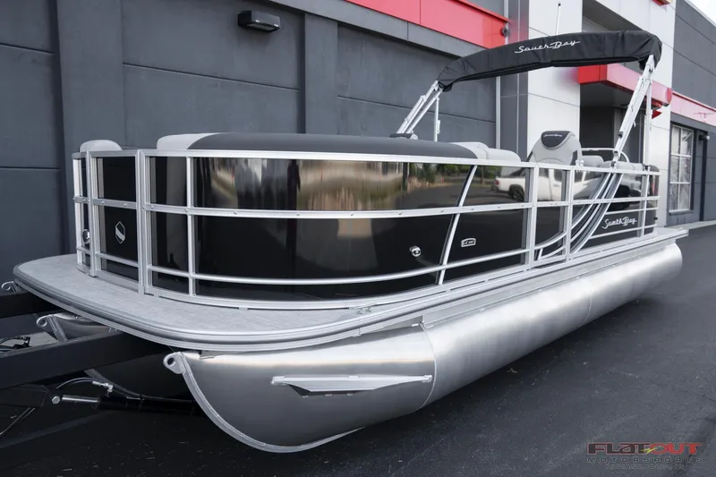 Slide: The Image of 2023 South Bay 224RSLE275 pontoon boat, sleek black design, docked outside a modern building. - 2