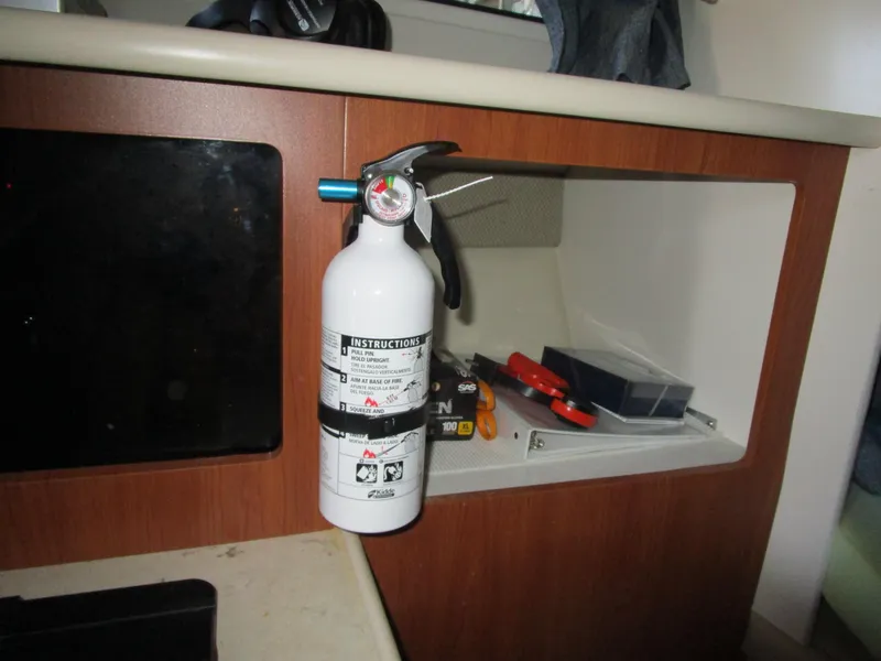 Slide: The Image of Fire extinguisher mounted inside 2005 Bayliner 285 boat cabin with storage compartment. - 24