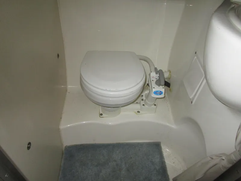 Slide: The Image of 2005 Bayliner 285 boat bathroom with compact marine toilet and blue mat. - 33