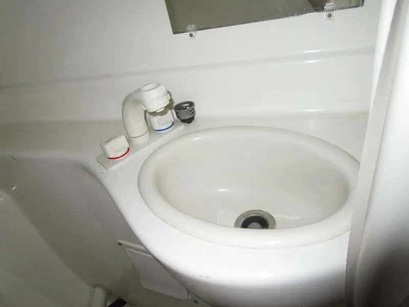 Slide: The Image of Compact bathroom sink in a 2005 Bayliner 285 boat, featuring a white basin and faucet. - 34