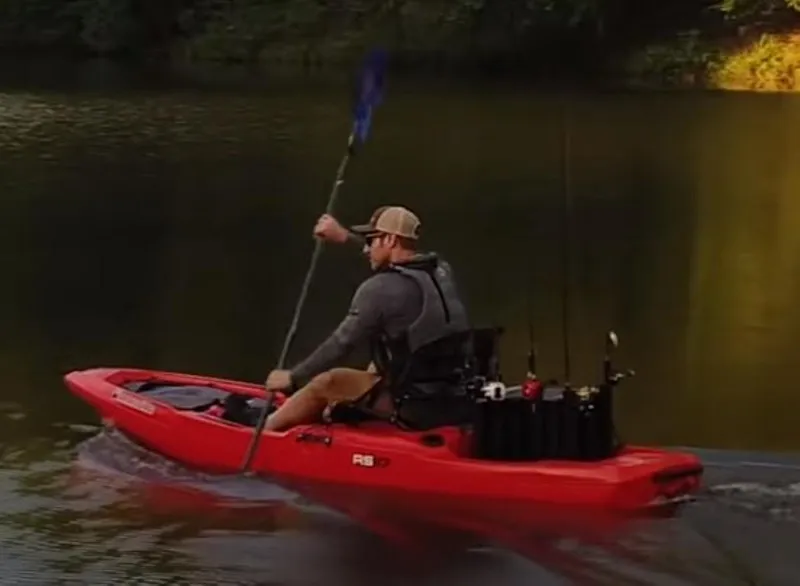 Slide: The Image of Man paddling a 2023 Bonafide RS117 kayak on a calm lake. - 9