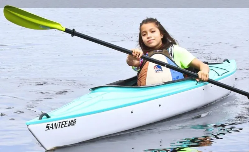 Slide: The Image of Young girl kayaking in a 2023 Hurricane Kayaks Santee 126 Sport on calm water. - 2