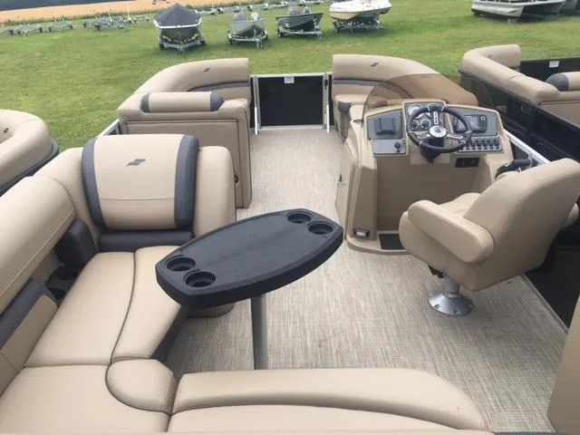 Slide: The Image of 2023 Starcraft EX 24 Q pontoon boat interior with beige seating and control console. - 2