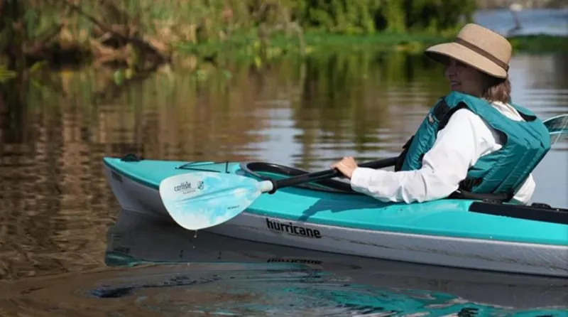 Slide: The Image of Woman kayaking in a 2023 Hurricane Kayaks Prima 110 Sport on a calm river. - 8