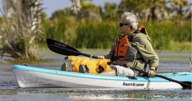 Slide: The Image of Man kayaking in a 2023 Hurricane Kayaks Skimmer 106 on a calm lake. - 6