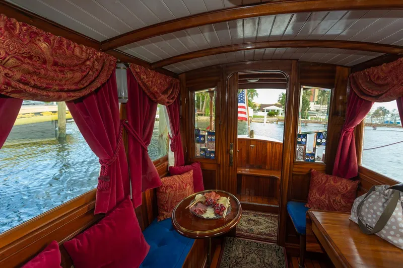 Slide: The Image of Luxurious interior of a 1910 Classic Gentleman’s Commuter yacht with red velvet curtains and wooden finish. - 14