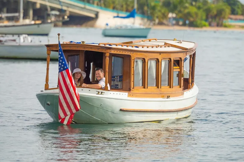 Slide: The Image of Classic 1910 Gentleman’s Commuter yacht with American flag on calm water. - 15