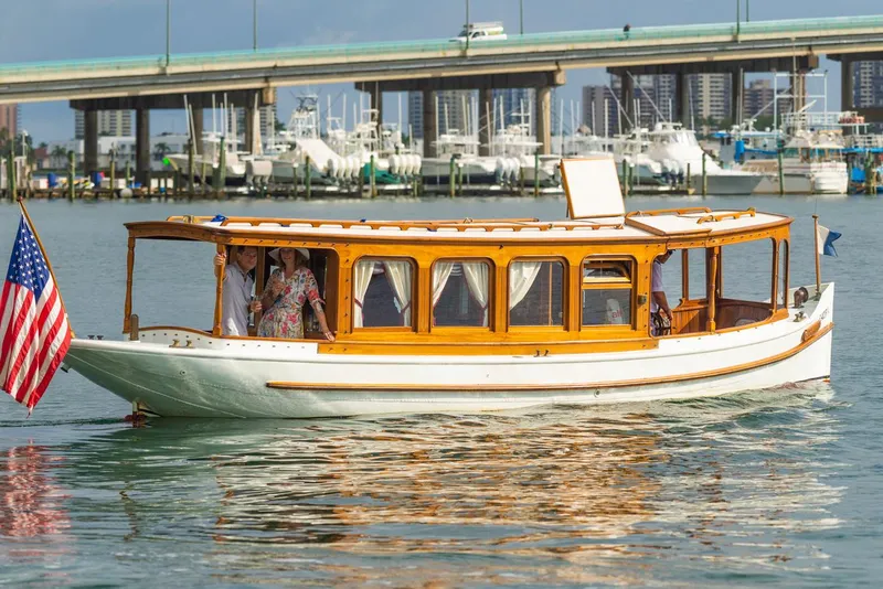 Slide: The Image of Classic 1910 Gentleman’s Commuter yacht cruising near a marina with a bridge in the background. - 3