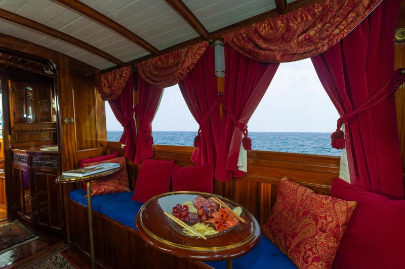 Slide: The Image of Luxurious interior of a 1910 Classic Gentleman’s Commuter yacht with red curtains and ocean view. - 7