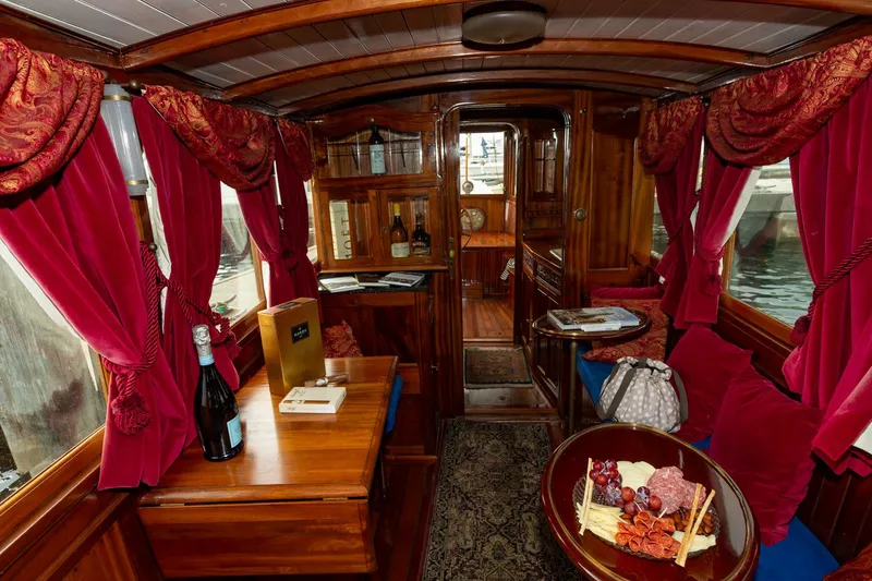Slide: The Image of Luxurious interior of a 1910 Classic Gentleman’s Commuter yacht with red curtains and wooden furnishings. - 8