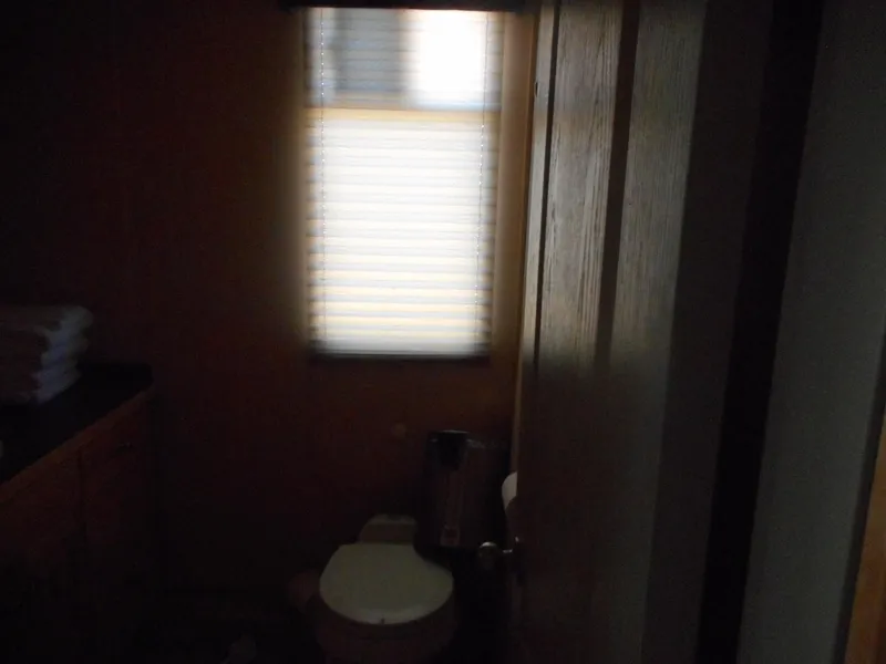 Slide: The Image of Dimly lit bathroom with a toilet, window, and countertop in a 2005 Twin Anchors Caspian share #9. - 9