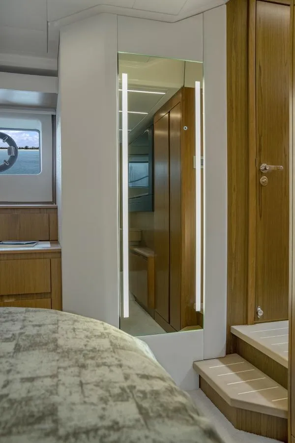 Slide: The Image of Interior of 2025 Tiara Yachts EX60, featuring modern wooden finishes and a well-lit mirror. - 22