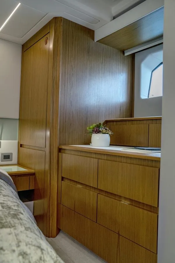 Slide: The Image of 2025 Tiara Yachts EX60 interior cabin with wooden cabinetry and porthole window. - 24