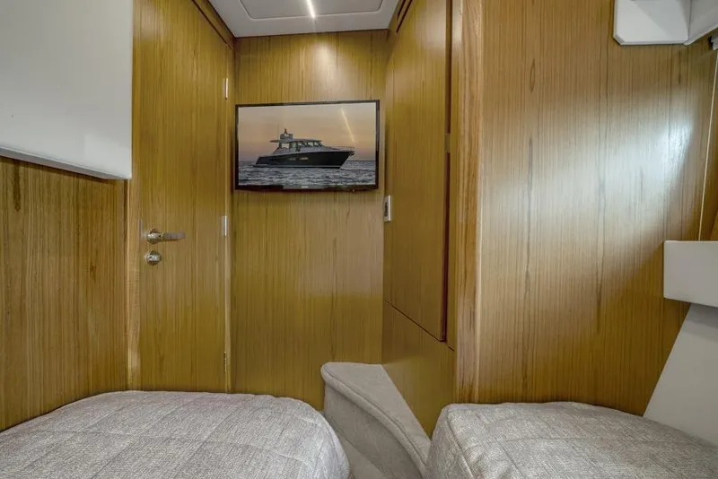 Slide: The Image of 2025 Tiara Yachts EX60 cabin interior with twin beds and wall-mounted TV. - 32