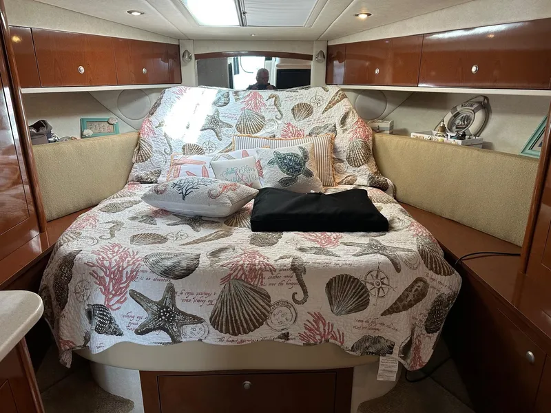 Slide: The Image of 2008 Sea Ray 330 Sundancer cabin with a seashell-themed bedspread and wooden cabinetry. - 20
