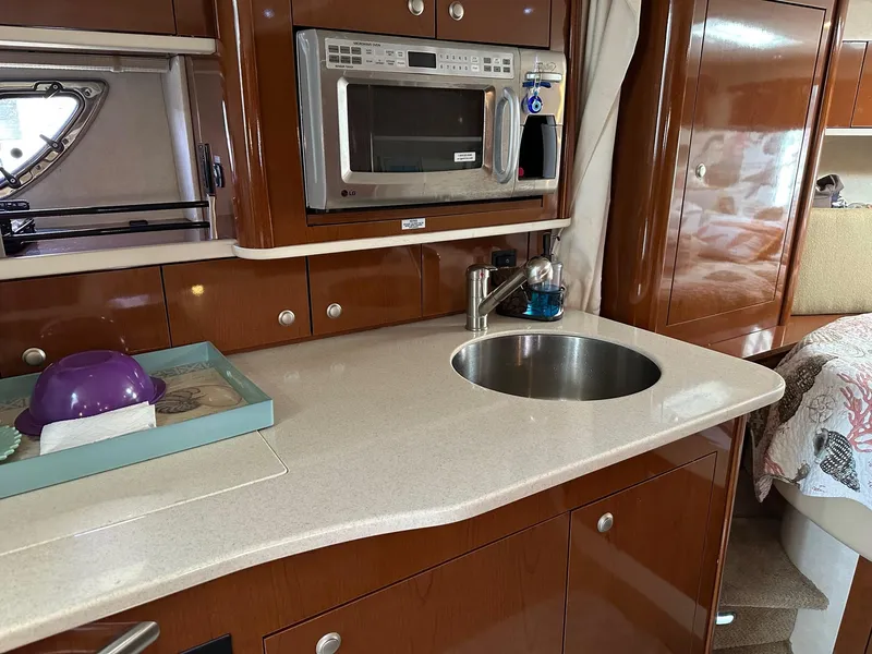 Slide: The Image of 2008 Sea Ray 330 Sundancer galley with microwave, sink, and wooden cabinetry. - 21