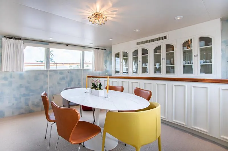 Slide: The Image of Elegant dining area in a 1966 Burger Classic yacht with modern decor and floral centerpiece. - 14