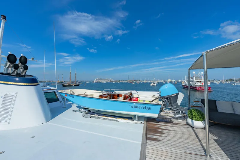 Slide: The Image of Classic 1966 Burger yacht with a small boat on deck, overlooking a busy harbor. - 50