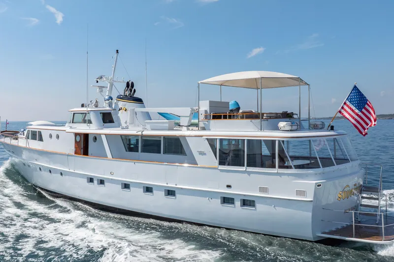 Slide: The Image of Classic 1966 Burger yacht cruising on open water with American flag. - 51