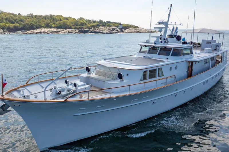 Slide: The Image of Classic 1966 Burger yacht cruising on serene waters near a rocky shoreline. - 53