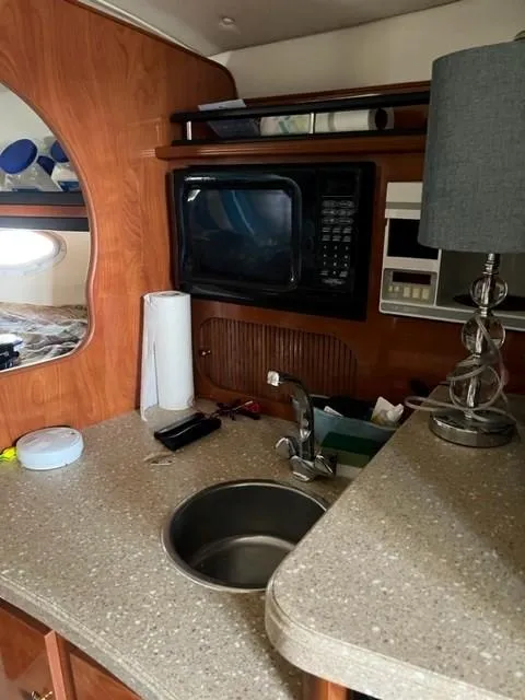 Slide: The Image of 2005 Rinker Fiesta Vee 320 boat interior kitchen with sink, microwave, and lamp. - 10