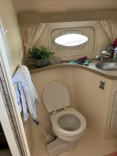 Slide: The Image of 2005 Rinker Fiesta Vee 320 boat bathroom with toilet, sink, and porthole window. - 23