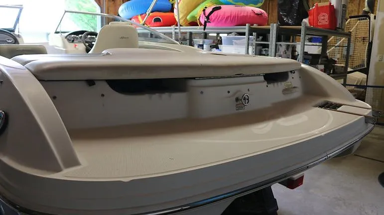 Slide: The Image of 2005 Sea Ray 200 Sport boat rear view in storage with colorful inflatables in the background. - 17