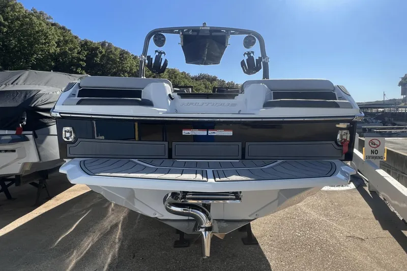 Slide: The Image of 2024 Nautique Super Air Nautique GS24 boat docked, rear view, sunny day. - 15