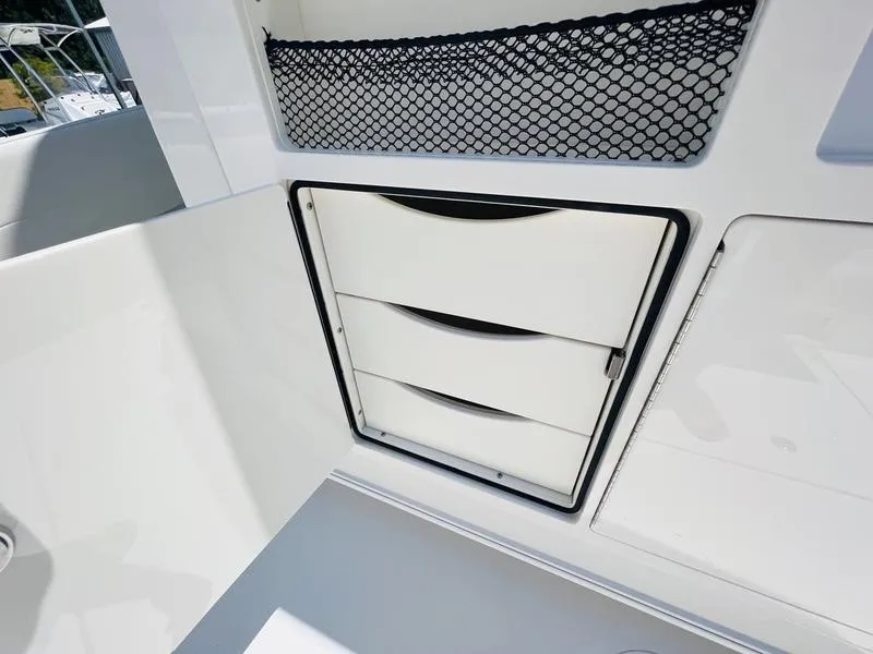 Slide: The Image of 2024 Sailfish 360 CC boat storage compartment with drawers and netted shelf. - 18