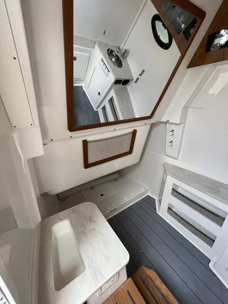 Slide: The Image of 2024 Sailfish 360 CC boat interior with sink, mirror, and storage compartments. - 29
