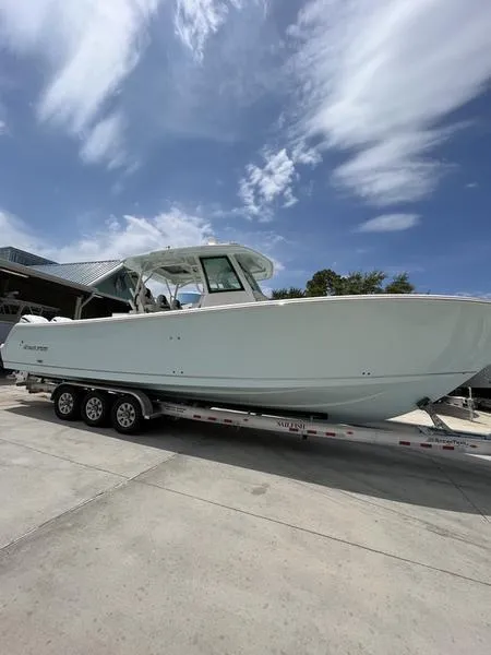 Slide: The Image of 2024 Sailfish 360 CC boat on a trailer under a partly cloudy sky. - 51