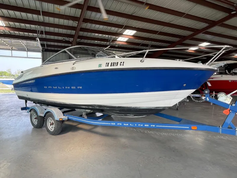 The Image of 2007 Bayliner 212 boat on a trailer in a covered storage area. - 0