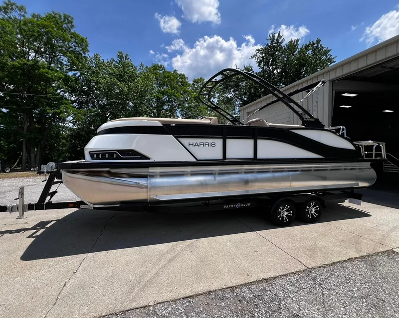 Slide: The Image of 2024 Harris Grand Mariner 230 pontoon boat on a trailer outside a garage. - 14