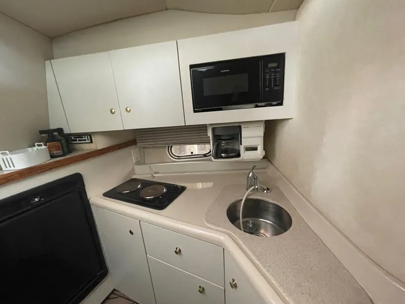 Slide: The Image of 1997 Cruisers Yachts 3375 Esprit galley with microwave, stove, sink, and storage cabinets. - 11