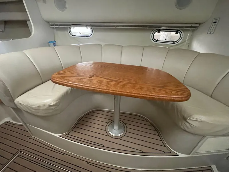 Slide: The Image of 1997 Cruisers Yachts 3375 Esprit interior dining area with wooden table and cushioned seating. - 15