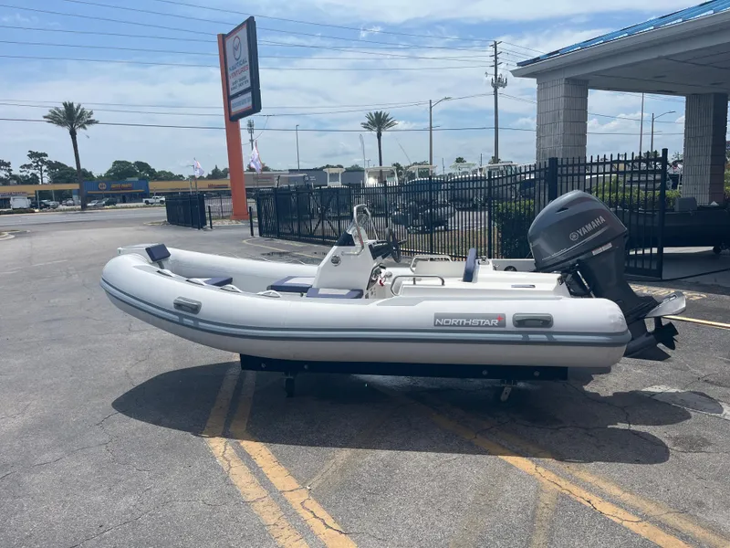 Slide: The Image of 2022 Northstar Axis 4.2 inflatable boat with Yamaha outboard motor, parked outdoors. - 8